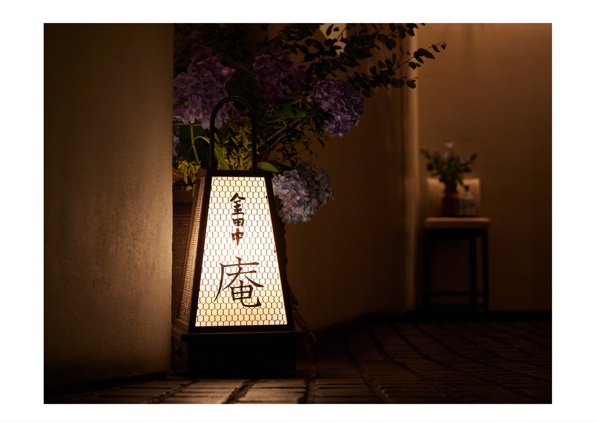 金田中 庵｜夜の店構え。行灯の灯りと花